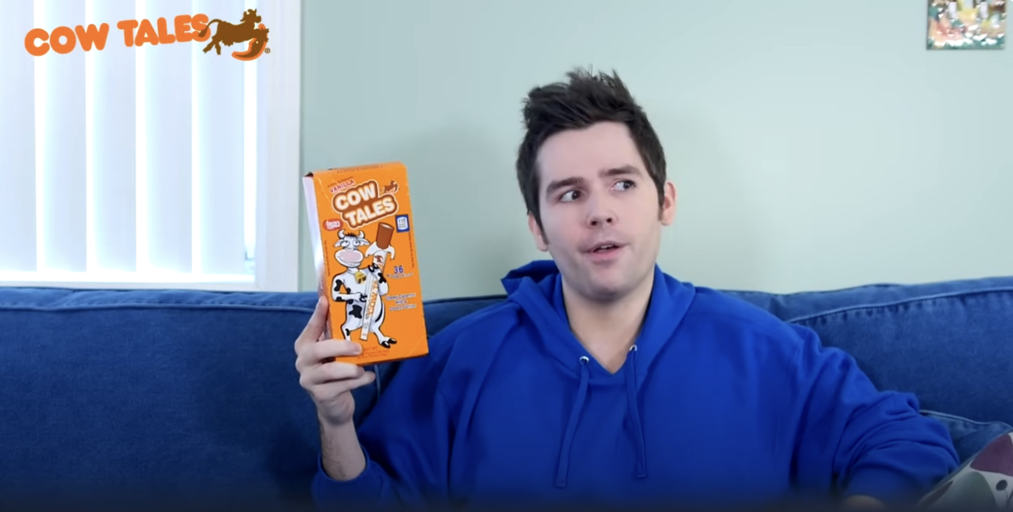 man sitting on couch holding a box of Cow Tales