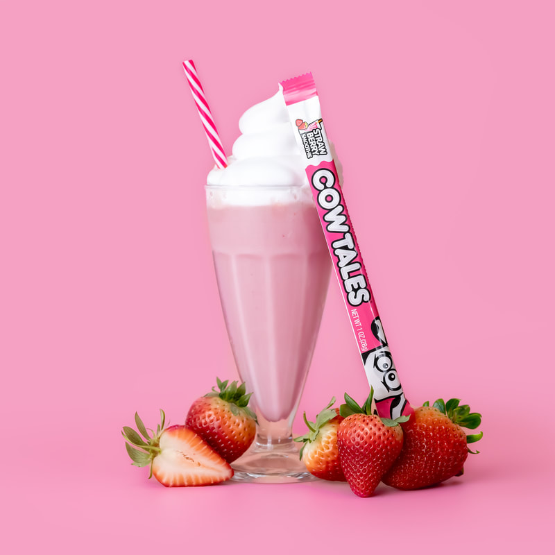 Strawberry Smoothie Cow Tale leaning up against a smoothie with whip cream and strawberries. 