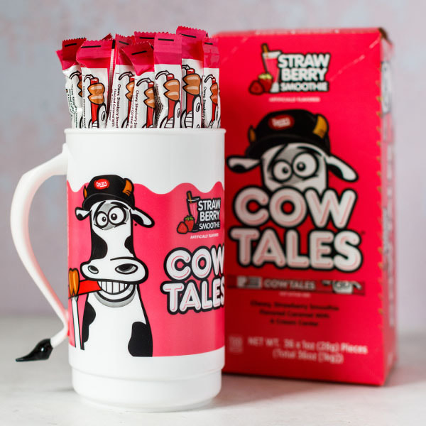 100 ct. Strawberry Milkshake Cow Tales in a mug with a carton sitting in the background