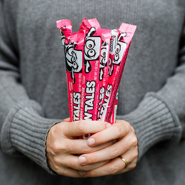 A person holding a handful of Strawberry Milkshake Cow Tales.