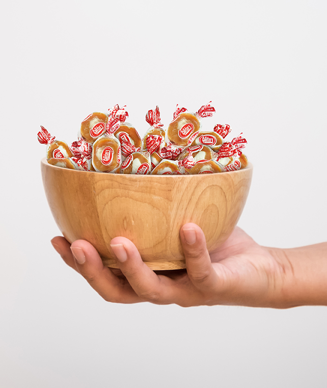 hand holding a basket of Caramel Creams candy