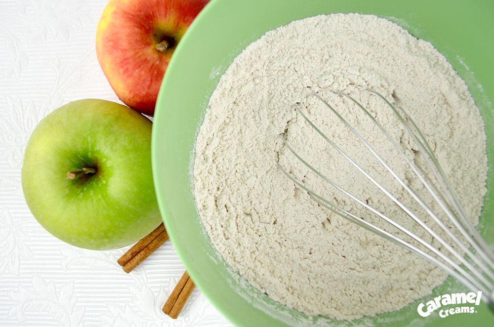 Some flour and a whisk in a green mixing bowl.