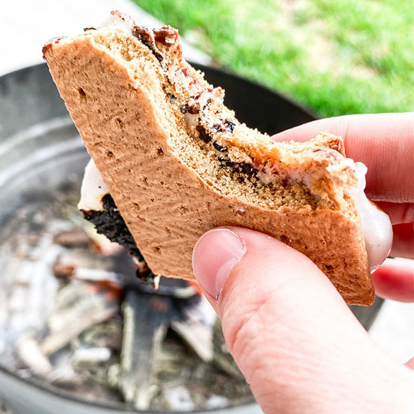 S'more with a bite taken out, showing melted chocolate and marshmallow between graham crackers